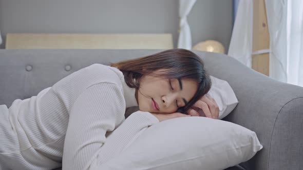 Exhausted or bored young sleepy woman falls down on sofa at home alone.