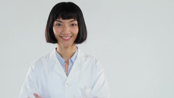 Female doctor standing with arms crossed against white background  alt