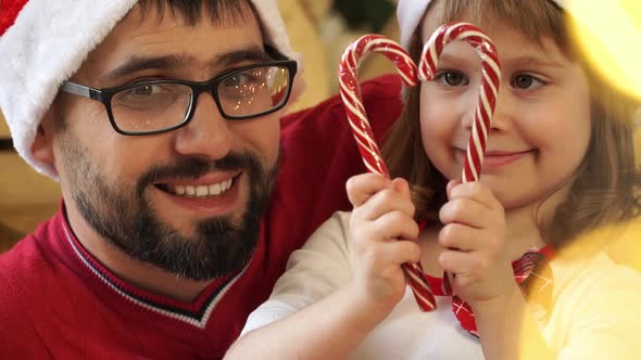 Father with Girl Make Heart of Cane Lollipop Look at Camera and Smile alt