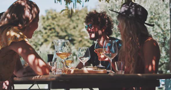 Nice-looking young friends eating and tasting wine in a farmhouse alt