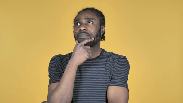 Thinking Casual African Man with New Plan Isolated on Yellow Background alt