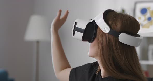 Woman Is Using Headmounted Display Touching Virtual Screen By Hand Swiping and Tapping Portrait of alt