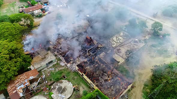 Aerial view rising away from a building fire, a structure smoking on the countryside, in Mexico, Cen alt