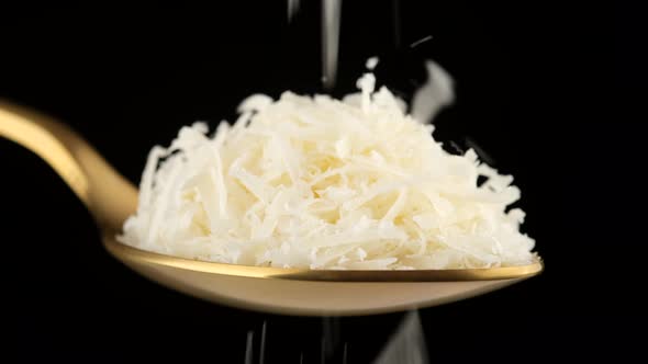 Pour grated cheese parmesan in golden spoon. Parmesan is Falling alt