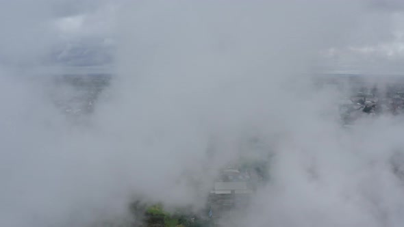 Flying Through a Cloud of Smoke Over a View of a Picturesque Green Town alt