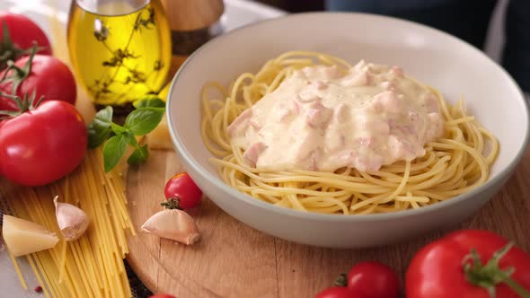 Making Pasta Carbonara  Adding Cream Sauce with Pancetta to Spaghetti in Ceramic Dish alt