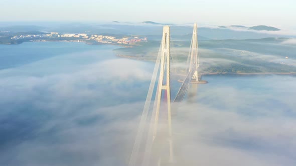 The Pylons of the Giant Cablestayed Bridge Rise Above the Seaside Morning Fog alt