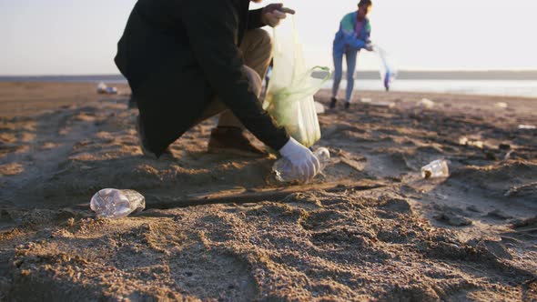 Close Up Shot of Young Man Picking Up Plastic Bottles on the Beach Slow Motion alt