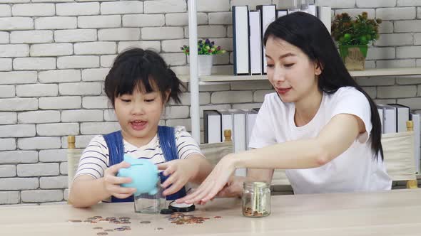 Mother teaches her daughter to save money through a piggy bank alt
