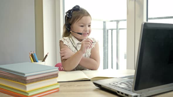 Features of Distance Learning. Online Lesson. Little Girl Communicates with a Teacher Via the alt