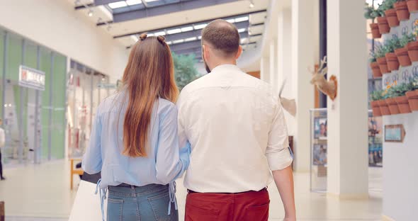Beautiful Young Couple Worth Walking Along the Shopping Center Holding Hands alt