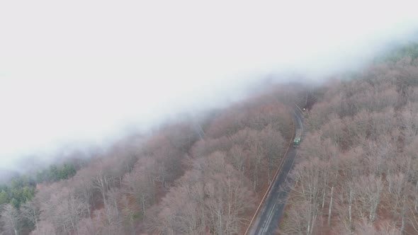 Drone Follows Fast Driving Truck on Forest Road Covered in Fog alt