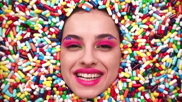 Beautiful girl acting inside a colored background made with pills alt