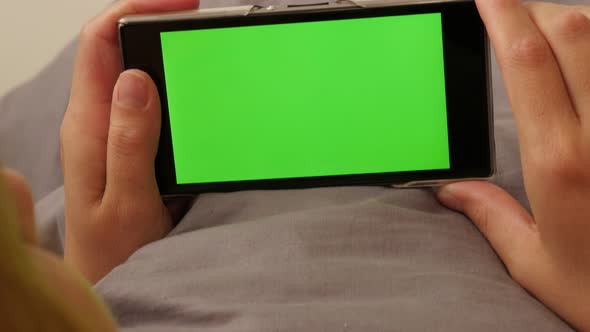 Woman in bed surfing through internet pages on green screen mobile  4K 2160p UltraHD footage - Femal alt
