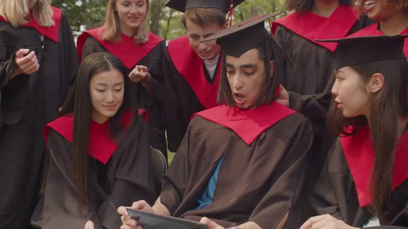 Portrait of Happy Multiracial Graduates Sharing Tablet Pc at Graduation Day alt