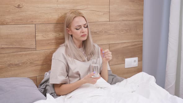 Young Woman Ill with Flu at Home Sitting on Bed Alone