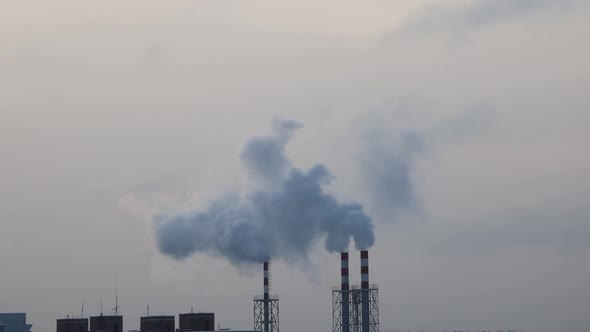 Dark smoke comes out of a boiler room chimney on a cloudy winter day. Environmental pollution.