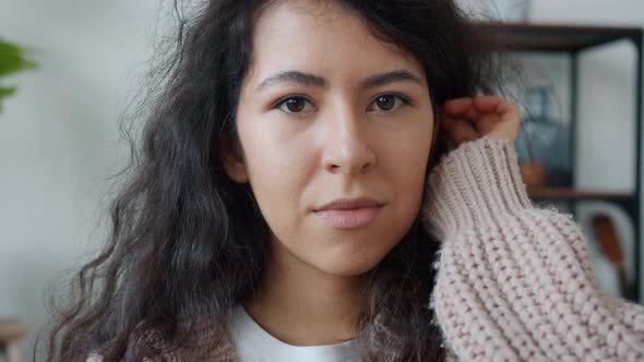 Portrait of Beautiful Mixed Race Girl Touching Curly Hair and Smiling Looking at Camera at Home alt