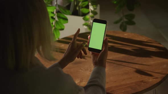 Handheld Close Up of a Caucasian Woman Hand Holding Smart Phone with Green Screen Swiping Sideways alt