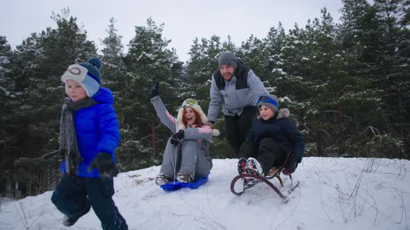 Winter Holidays Happy Married Couple Together with Their Little Sons Sledding Down Hill in Winter