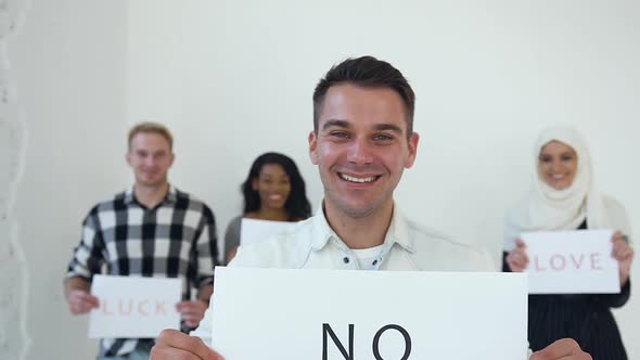 Young Man Posing on Camera with Poster with Words "No Racism" alt