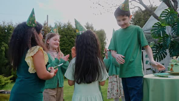 Children Congratulate a Girl on Her Birthday at a Backyard Party on a Sunny Day alt