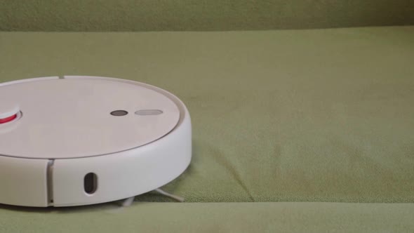Robot vacuum cleaner vacuuming the bed in the bedroom. Smart home with automated devices alt
