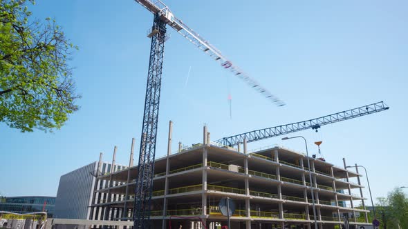 Construction of a modern office with working cranes, time-lapse alt