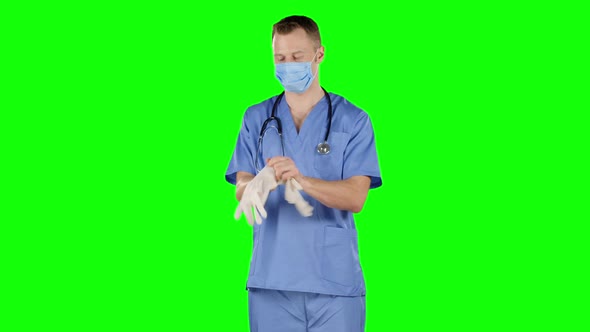 Healthcare Worker Putting on Medical Gloves. Green Screen alt