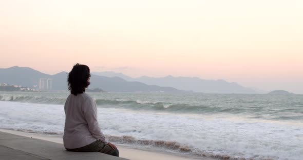 An Aged Woman Wearing a Protective Mask is Doing Exercises and the Sea View Wearing a Covid19 Mask alt