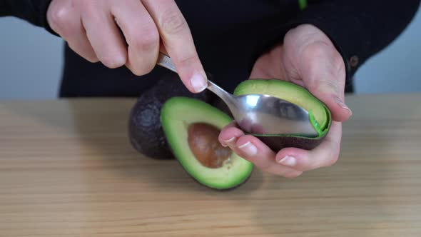 Young woman taking a green avocado with a spoon