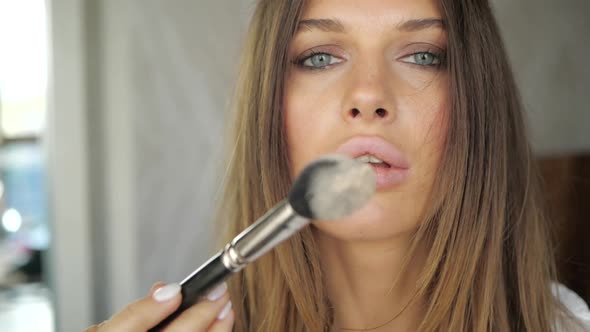 Beautiful Girl Blows Powder From the Brush Directly Into the Camera