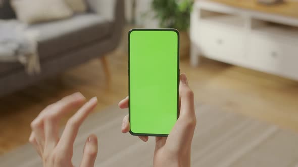 Back View of Woman at Living Room Using Phone With Green Mockup Screen Chroma Key Without Track alt