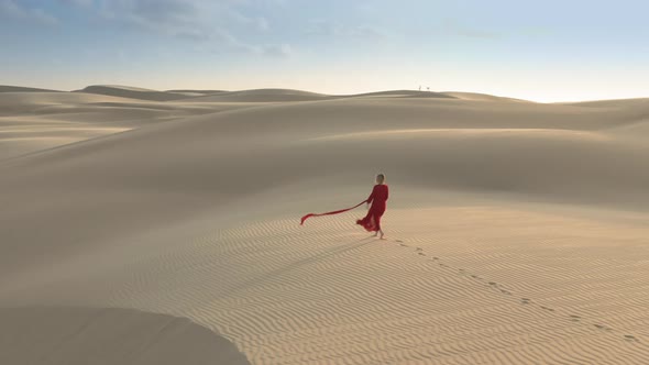  Aerial View of the Model in a Fashionable Red Dress Walking in Desert Nature alt