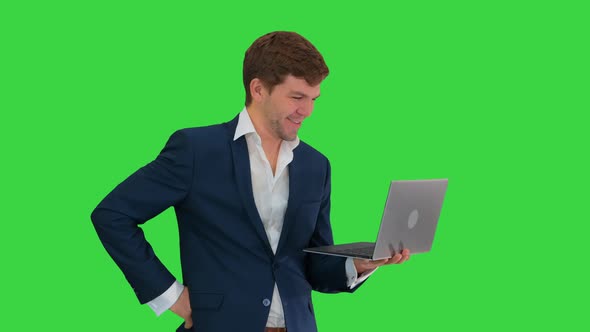Smiling Young Businessman Using Laptop While Standing on a Green Screen, Chroma Key alt