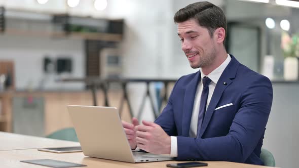 Cheerful Businessman Talking on Video Call on Laptop in Office  alt