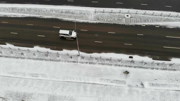 white car driving by empty winter snow road, aerial shot