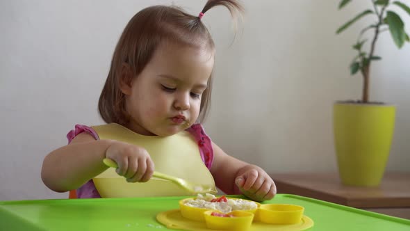Close Up of Lovely Baby Girl Eating Have Breakfast Eggs Vegetables Sausage By Herself at Home alt