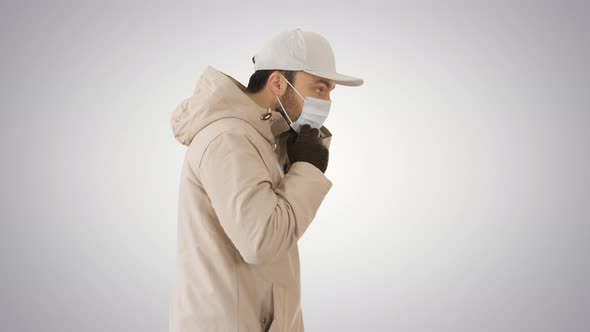 Winter-like Dressed Caucasian Man Putting on Medical Mask on Gradient Background. alt