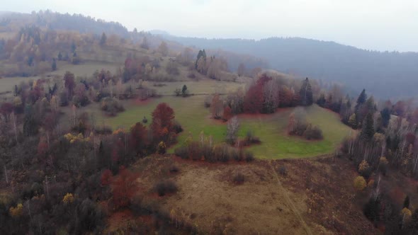 Aerial Drone Footage View: Flight over autumn mountain with forests and fields.