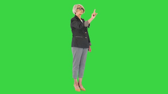 Senior Business Woman in Glasses Pointing on Buttons of a Virtual Screen on a Green Screen Chroma alt