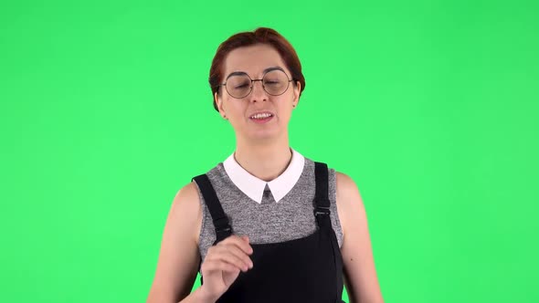 Portrait of Funny Girl in Round Glasses Is Waving Hand and Showing Gesture Come Here. Green Screen alt