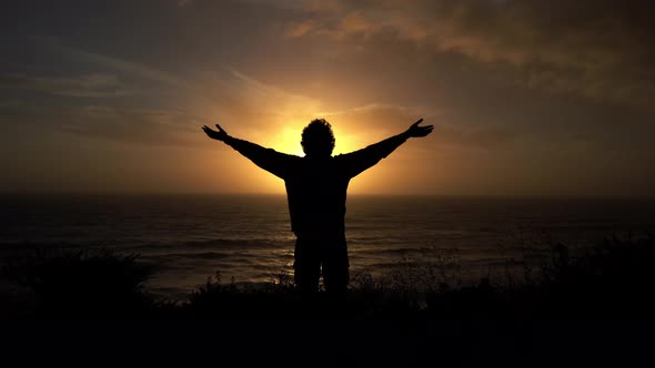 Man raising his arms against the sunset