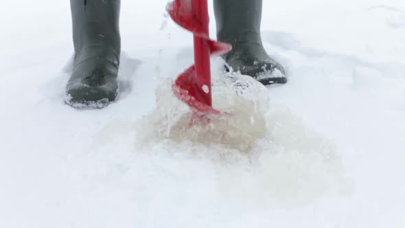 Winter Fisherman Uses Ice Screws alt