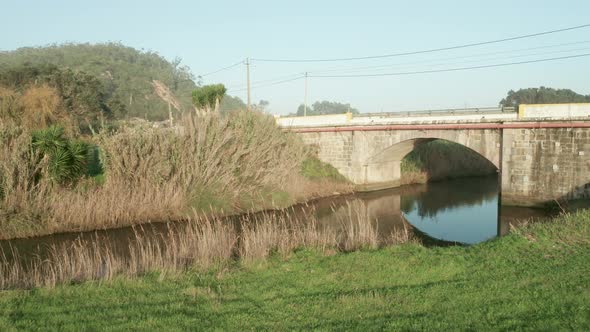 Quiet Lake Among Golden Grass With Arch Bridge In Alcobaca River Near Nazare In Portugal. - Aerial P alt