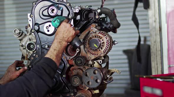 Car Mechanic Assembles Parts Of Car Engine With Cordless Screwdriver In The Repair Shop alt