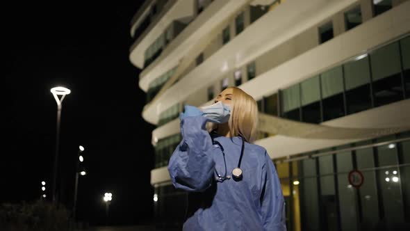 Young Female Medical Intern Takes Off Medical Mask During Night Shift alt