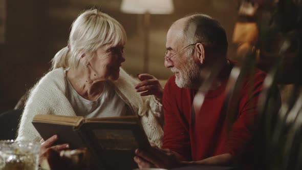 Happy Aged Couple Discussing Photos on Sofa alt