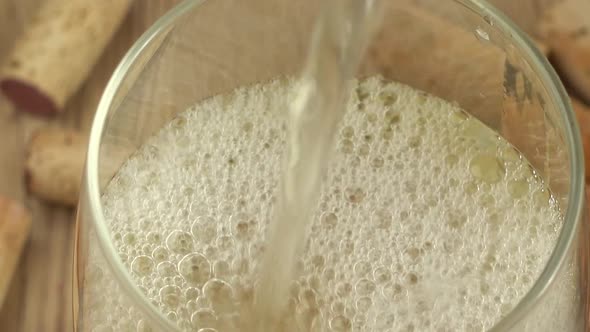 Wine is poured into a glass on the background of wine corks. alt