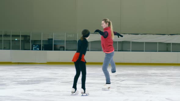 Figure skating girl circling around her professional trainer